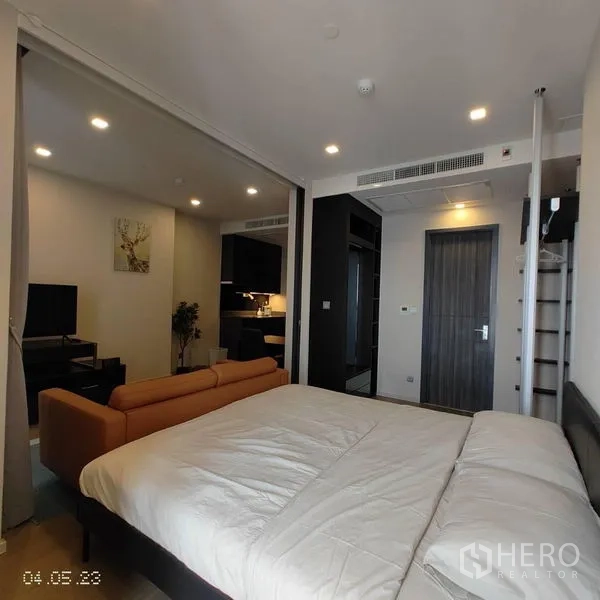 Condominium for rent in Watthana, Bangkok - Bright bedroom with king bed and sliding wall opening to the living area.