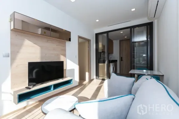 คอนโด ให้เช่าในWatthana, Bangkok - มุมมองจากโซฟาไปยังผนังทีวี โต๊ะทานอาหาร และฉากกระจกกั้นครัว