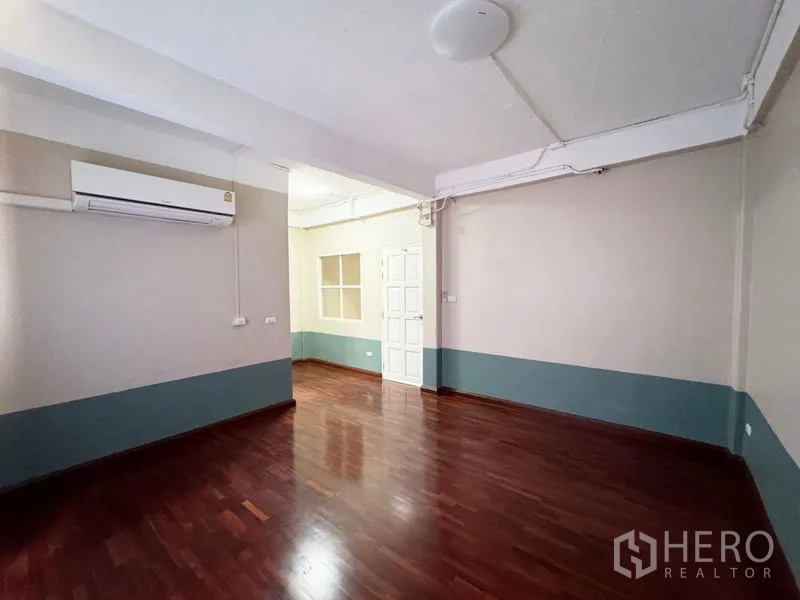 ทาวน์เฮาส์ ให้เช่าหรือขายในSuan Luang, Bangkok - ห้องโล่งพื้นไม้ ปรับอากาศ พร้อมประตูสีขาวและช่องหน้าต่าง