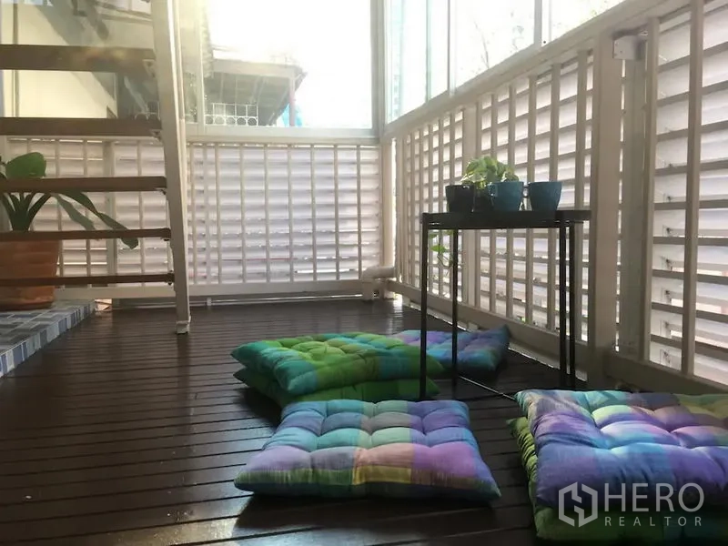 ทาวน์เฮาส์ ให้เช่าในBang Rak, Bangkok - ระเบียงปิดพื้นไม้ ผนังระแนง เบาะนั่งพื้น โต๊ะวางกระถางต้นไม้ และบันได