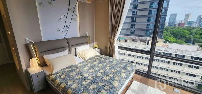 คอนโด ให้เช่า - ห้องนอนมุมอาคาร วิวเมืองและสวนผ่านหน้าต่างสูงจรดเพดาน