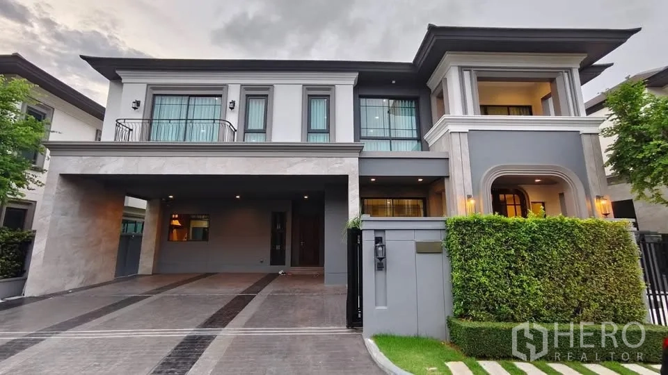 Detached House for rent or sale in Lat Krabang, Bangkok - Modern two-storey house facade with balcony, wide carport, and gated entry.
