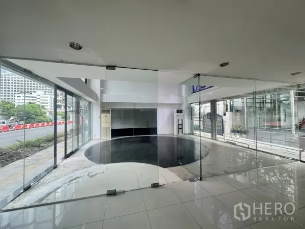 Retail Space for rent in Sathon, Bangkok - Bright double-height showroom with floor-to-ceiling windows and a circular black tile feature facing the street.
