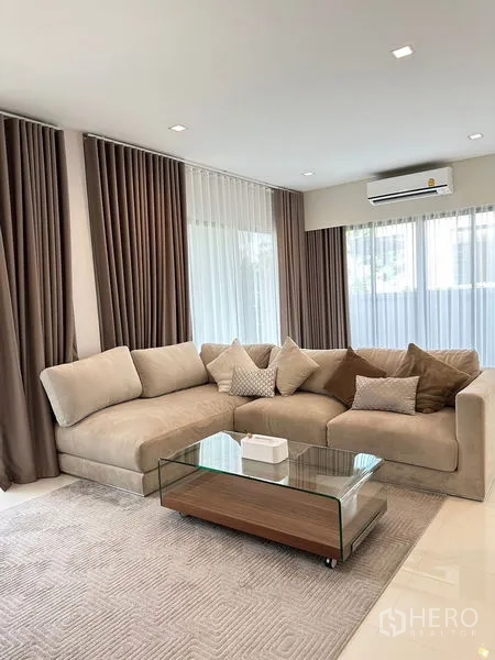 Detached House for rent or sale - Bright living room with L-shaped sofa, glass coffee table and large windows.