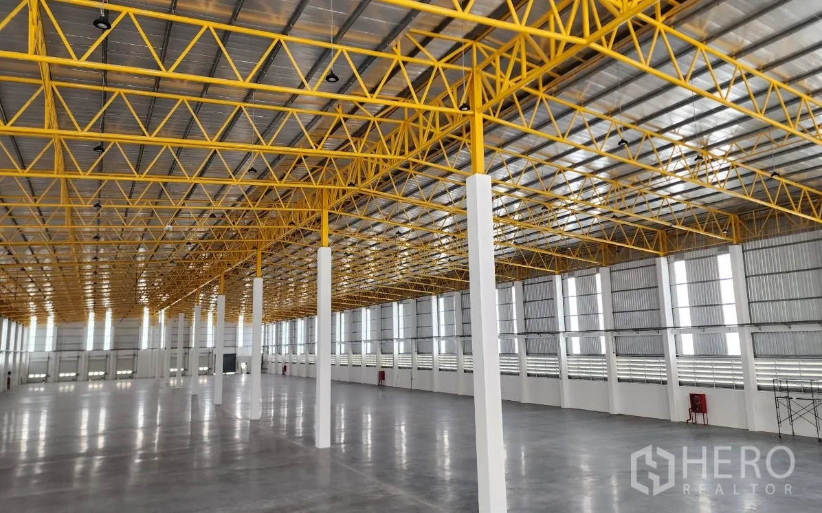 Warehouse for rent in Lat Krabang, Bangkok - Ceiling detail showing steel trusses, translucent roof panels, and a clear column layout inside the warehouse.