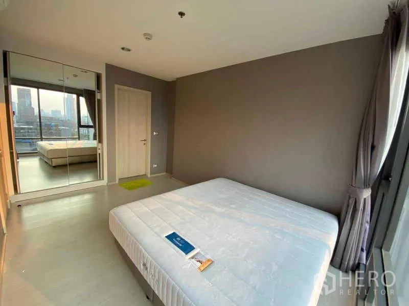 คอนโด ให้เช่าหรือขายในKhlong Toei, Bangkok - ห้องนอนสว่างพร้อมตู้เสื้อผ้าบานกระจกและหน้าต่างสูงจรดเพดานรับวิวสกายไลน์