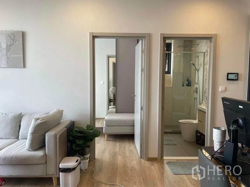 คอนโด ให้เช่าในKhlong Toei, Bangkok - พื้นที่นั่งเล่นเห็นโซฟา ประตูเข้าห้องนอน และห้องน้ำพร้อมฝักบัวกระจก