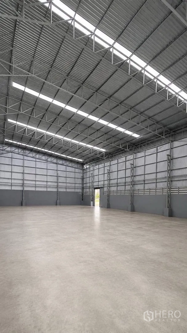 Warehouse for rent in Bang Khun Thian, Bangkok - Open-plan warehouse showing skylight roof panels, ventilation slats, and polished concrete floor.