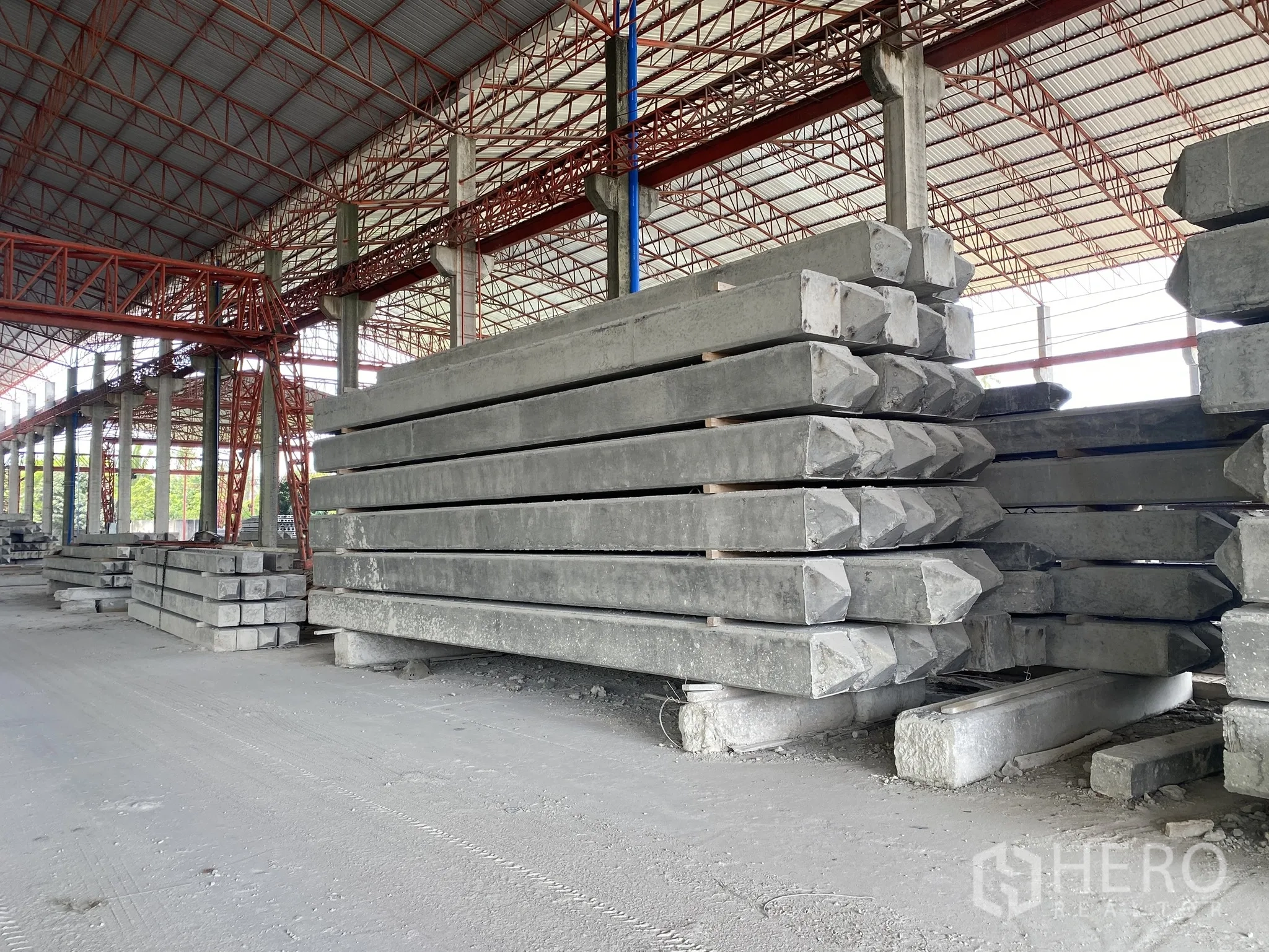 Factory for sale in Mueang Chon Buri, Chon Buri - Stacks of precast concrete piles stored under a roofed bay.