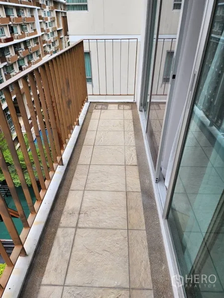 公寓 出租在Watthana, Bangkok - 狭长阳台，铺设地砖，连接推拉玻璃门。