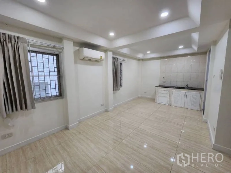 Home Office for rent in Khlong Toei, Bangkok - Multi-purpose room with kitchenette counter, tiled floor, air conditioner, and windows with security grilles.