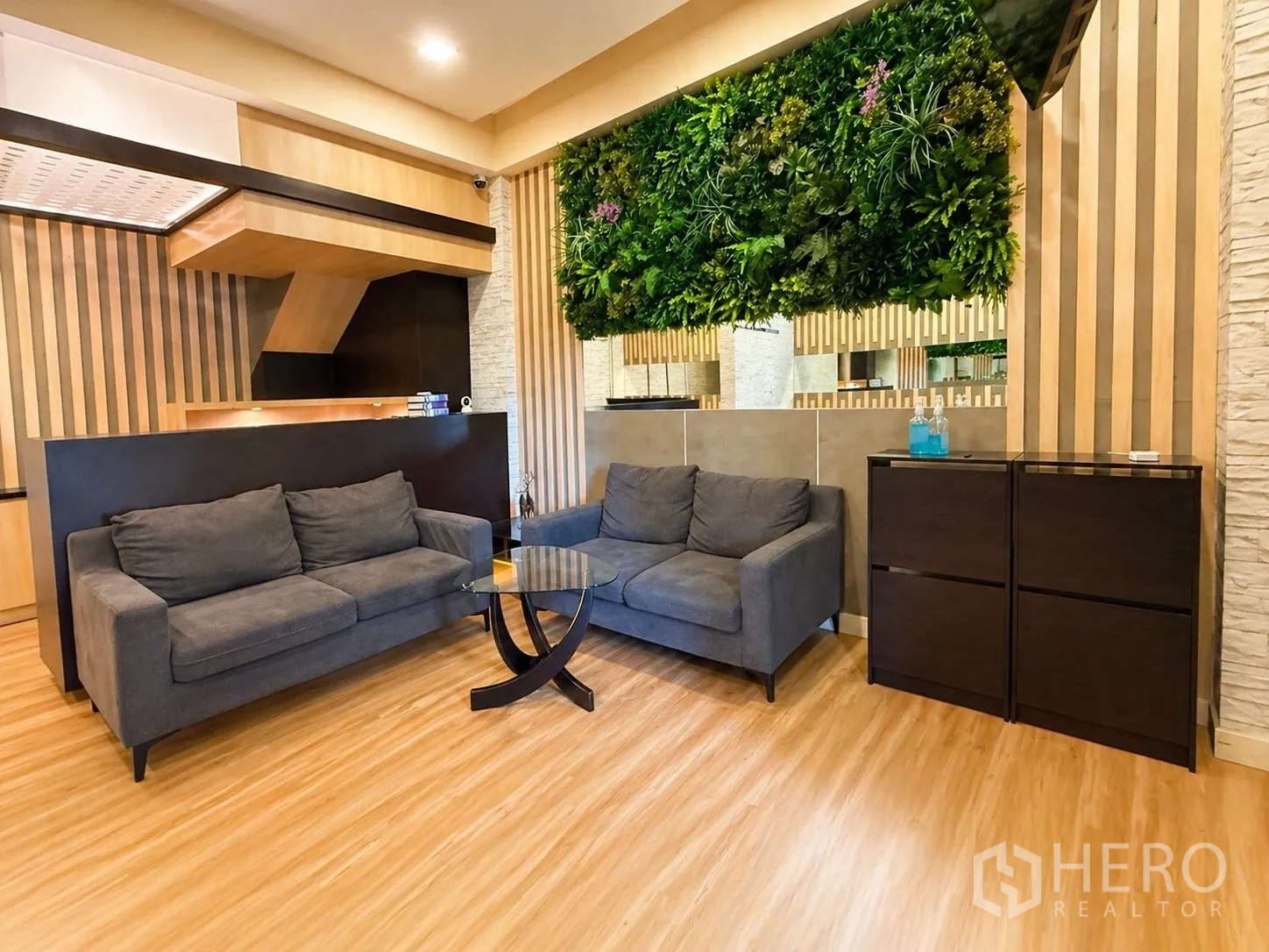 Home Office for rent or sale in Yan Nawa, Bangkok - Contemporary reception lounge with grey sofas, wood accents, and a green wall feature.