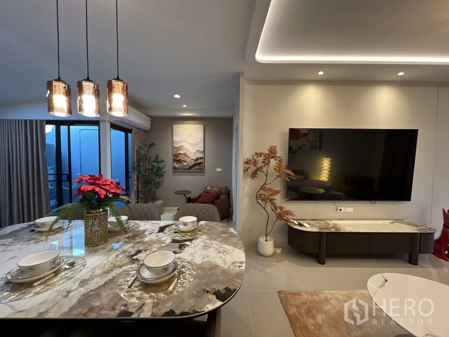 Townhouse for rent in Bang Phli, Samut Prakan - Dining space with pendant lights and a view of the TV wall and sliding glass door.