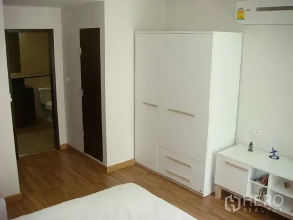 Apartment for rent in Khlong Toei, Bangkok - Second bedroom with white wardrobe, air conditioner and door to the bathroom.