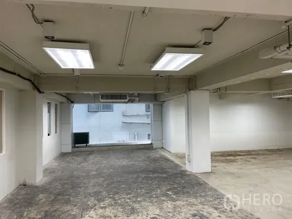 Office Space for rent in Ratchathewi, Bangkok - Open-plan office area with fluorescent lighting, exposed ceiling and a wide window in Ratchathewi.