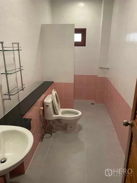 Detached House for sale in Bang Khun Thian, Bangkok - Long bathroom with pink and white tiles, toilet, sink and a small window.