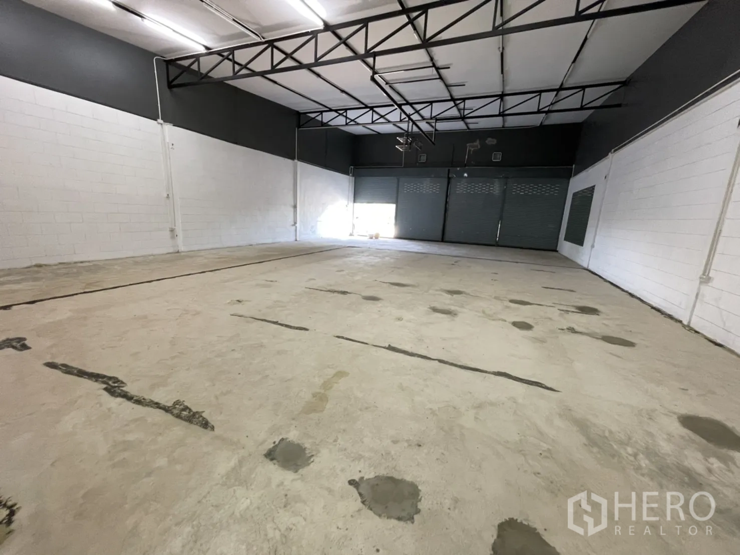 คลังสินค้า ให้เช่าในLam Luk Ka, Pathum Thani - โถงโกดังพื้นคอนกรีตเรียบ ผนังทาสีขาว และด้านหน้ามีประตูม้วน.