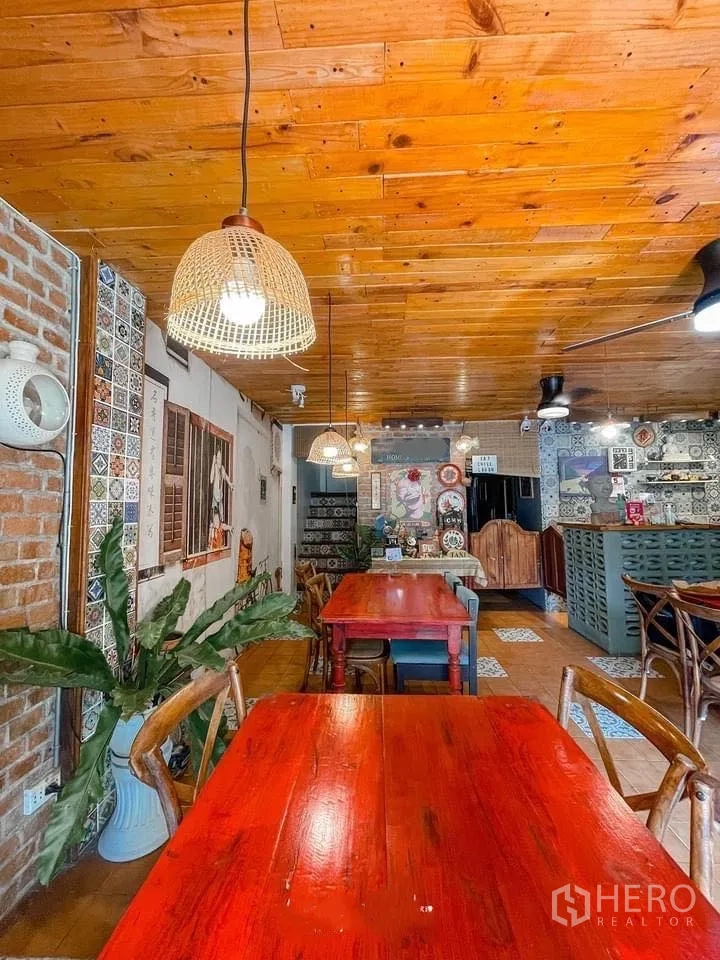 零售空间 for rent in Watthana, Bangkok - 用餐区配藤编吊灯、木天花、红桌与绿植。