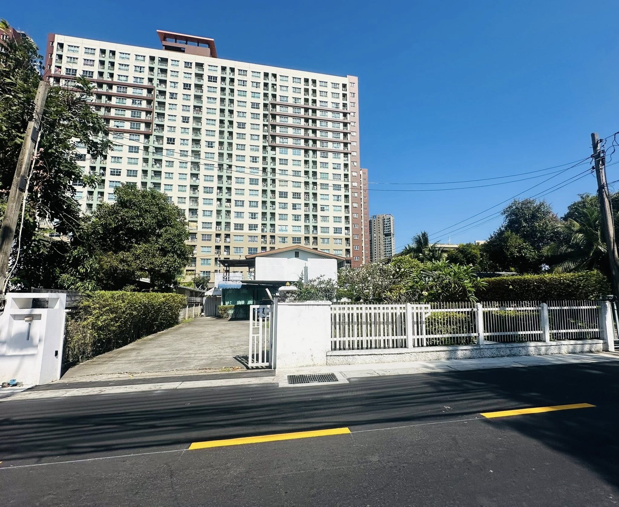 สำนักงานที่บ้าน ให้เช่าในChatuchak, Bangkok - แปลงโฮมออฟฟิศมีรั้วและทางเข้ารถ พื้นคอนกรีต มีคอนโดสูงด้านหลังในวันที่ท้องฟ้าแจ่มใส
