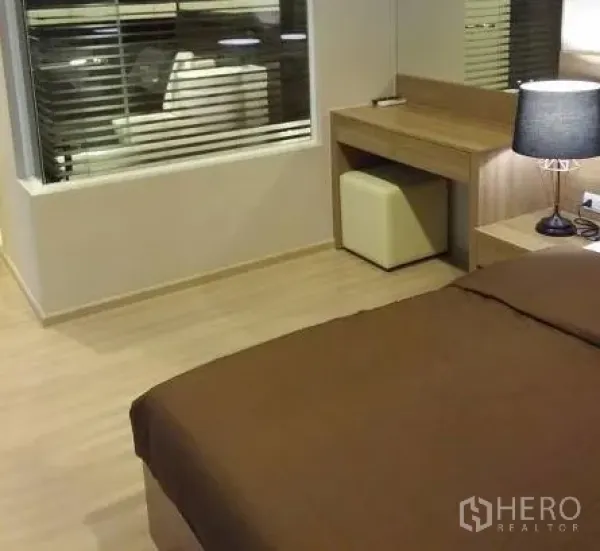 Condominium for rent in Sathon, Bangkok - Primary bedroom corner with built-in desk, mirror and window with blinds.