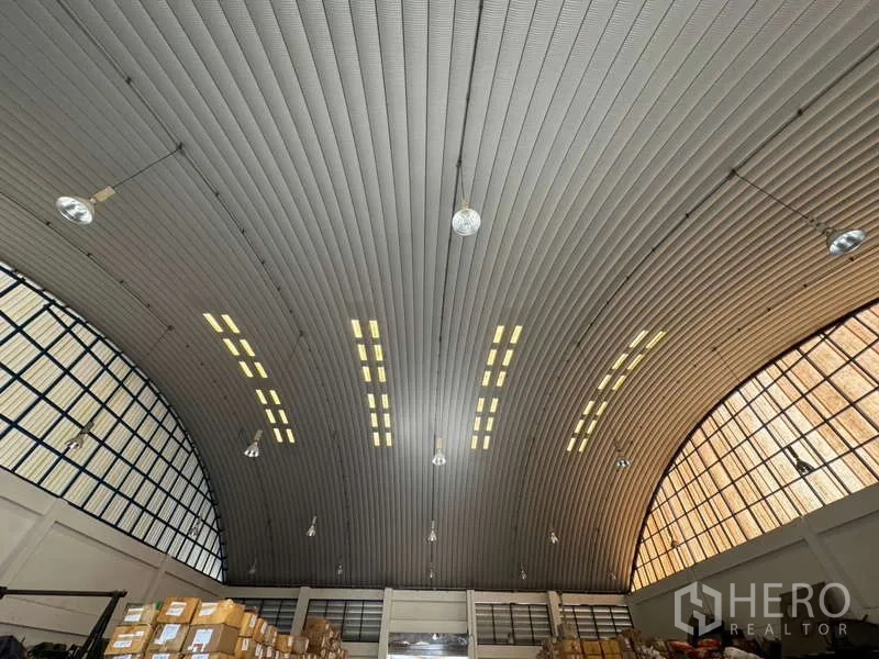 Warehouse for rent in Photharam, Ratchaburi - Close-up of curved insulated roof with hanging lights and daylight panels.