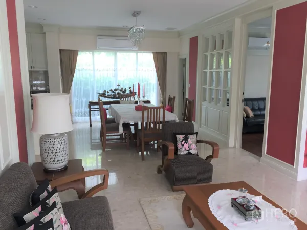Detached House for rent in Saphan Sung, Bangkok - Open-plan living and dining room with sofas, decorative wall panels and floor‑to‑ceiling windows.