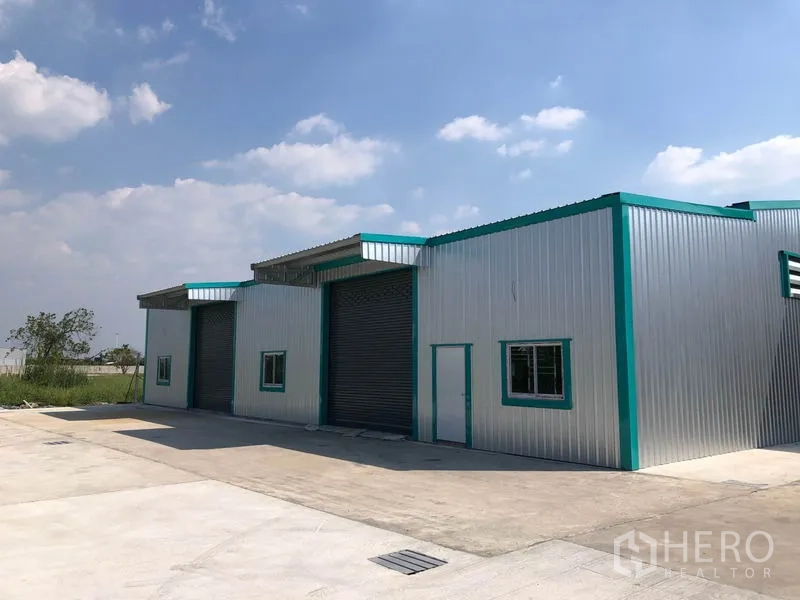 Warehouse for rent in Pak Kret, Nonthaburi - Modern metal-clad warehouse with three roller shutter doors and a wide concrete yard in Pak Kret.