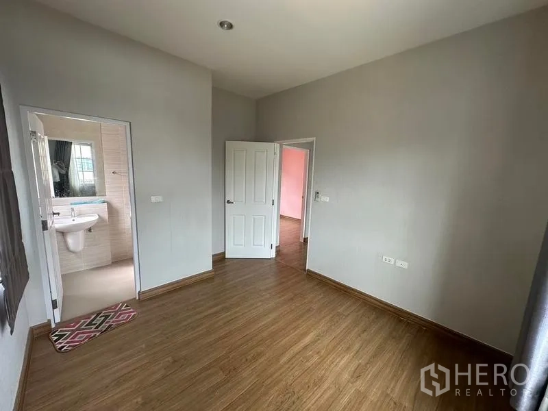 Detached House for sale in Bang Khen, Bangkok - Empty bedroom with wood flooring and a door to an en-suite bathroom.