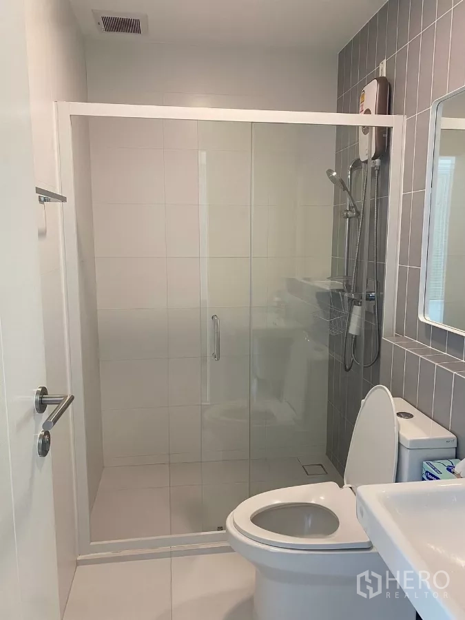 联排别墅 出租在Prawet, Bangkok - 现代浴室，玻璃淋浴间与白色瓷砖。