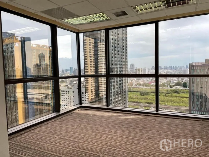 Office Space for rent - Corner office wrapped in floor-to-ceiling glass showcasing high-rise towers and green views.