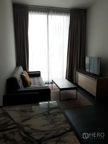 คอนโด ให้เช่าหรือขายในWatthana, Bangkok - ห้องนั่งเล่นสว่างพร้อมโซฟา โต๊ะกลาง ตู้วางทีวี และประตูกระจกเต็มบานพร้อมผ้าม่าน ในคอนโดใกล้อโศก