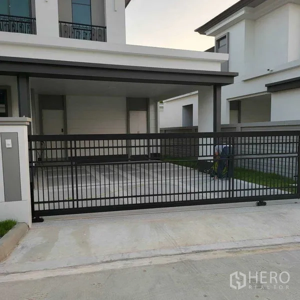 Detached House for rent in Mueang Pathum Thani, Pathum Thani - Covered carport behind black sliding gate of modern two-storey house