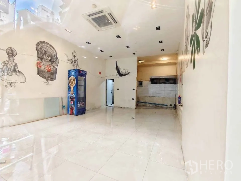 Retail Space for rent in Khlong Toei, Bangkok - Open-plan interior with white tile flooring, recessed lights, cassette air-conditioning, and wall art.