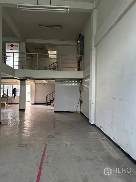 อาคารพาณิชย์ ให้เช่าในKhlong Toei, Bangkok - ชั้นลอยมีราวกันตกและบันได เหนือพื้นที่ค้าขายโล่ง ผนังสีขาวและพื้นคอนกรีต