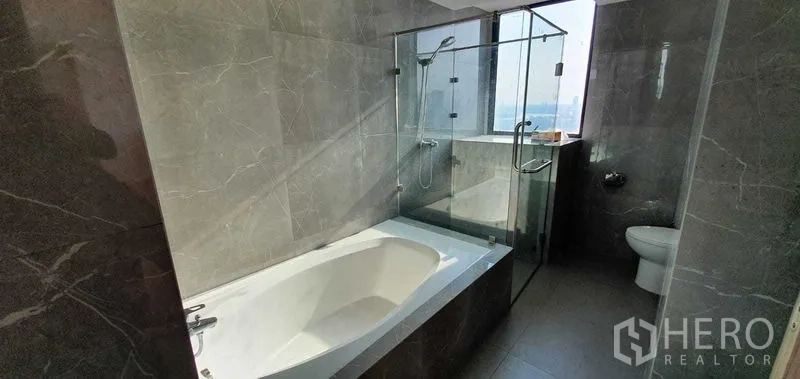 คอนโด ให้เช่าในKhlong Toei, Bangkok - ห้องน้ำพร้อมอ่างอาบน้ำและห้องอาบน้ำกระจกแยก เห็นวิวเมืองจากหน้าต่าง