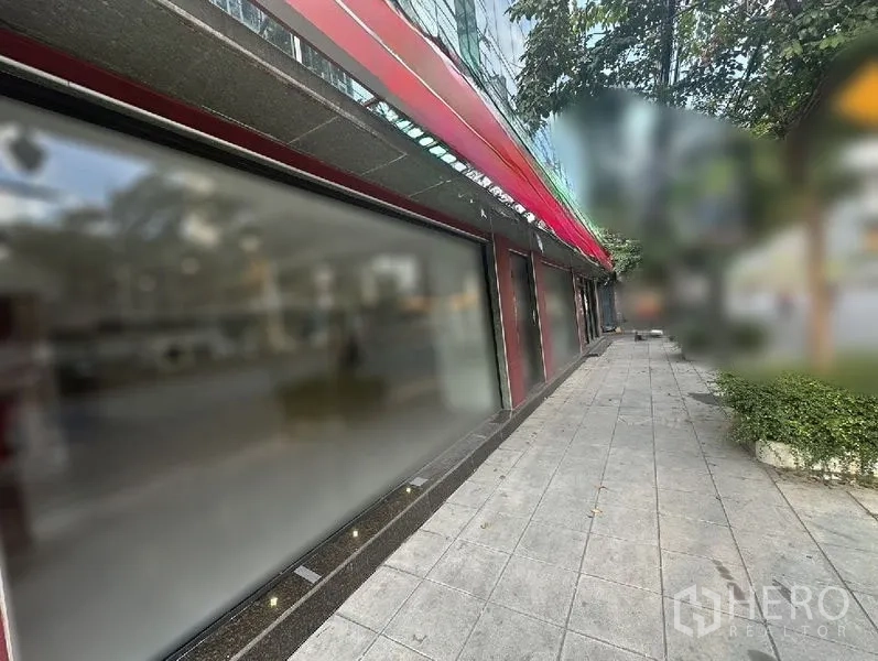 零售空间 出租在Bang Rak, Bangkok - 沿人行道延伸的玻璃店招与红色雨篷。