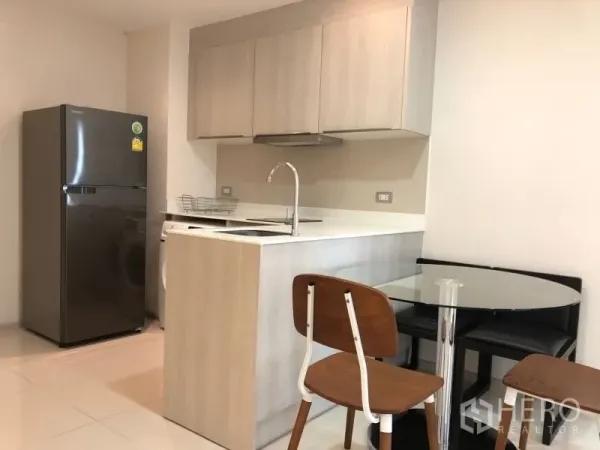 公寓 出售在Khlong Toei, Bangkok - 浅木色橱柜的现代厨房，带岛台与圆形玻璃餐桌