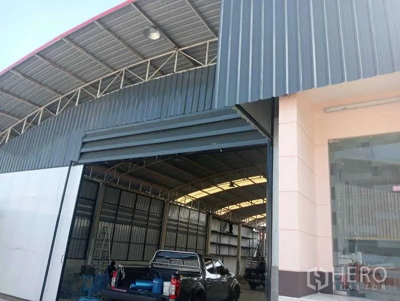 货栈 出租在Lam Luk Ka, Pathum Thani - 仓库入口特写，钢制卷帘门与玻璃办公室立面