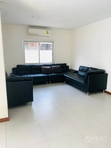 联排别墅 出租或出售在Huai Khwang, Bangkok - 转角客厅，L型黑色皮沙发，空调与百叶窗