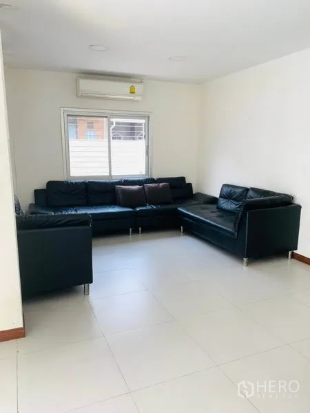联排别墅 出租或出售在Huai Khwang, Bangkok - 转角客厅，L型黑色皮沙发，空调与百叶窗