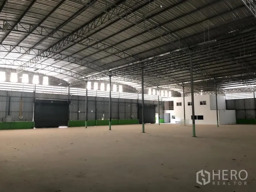 货栈 出租在Lat Krabang, Bangkok - 开阔仓库地面，可见多扇卷帘装卸门、天窗带和宽柱距。