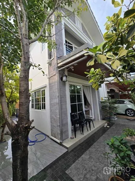 Detached House for rent in Thanyaburi, Pathum Thani - Two-storey house exterior with sliding doors, small patio seating and landscaped garden.