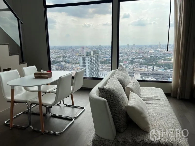 公寓 出租在Ratchathewi, Bangkok - 餐区与沙发临落地窗，城市景观开阔。