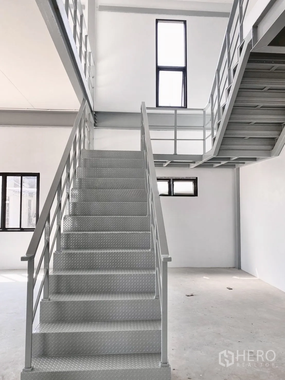 Warehouse for rent in Bang Bo, Samut Prakan - Stairwell with metal steps and tall windows in the office block.