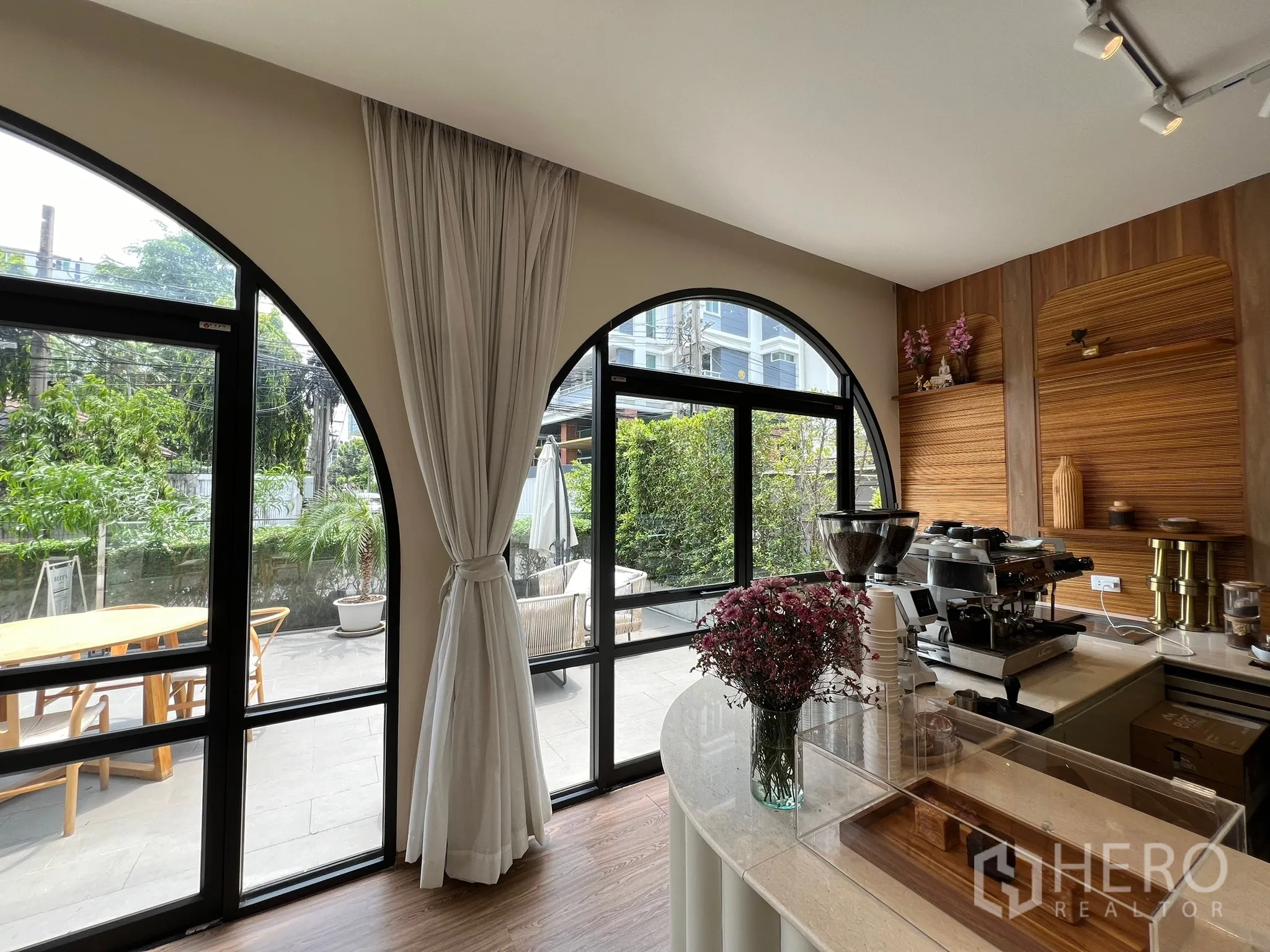 零售空间 出租在Watthana, Bangkok - 服务吧台配咖啡设备与木质背景墙，拱形窗面向露台。