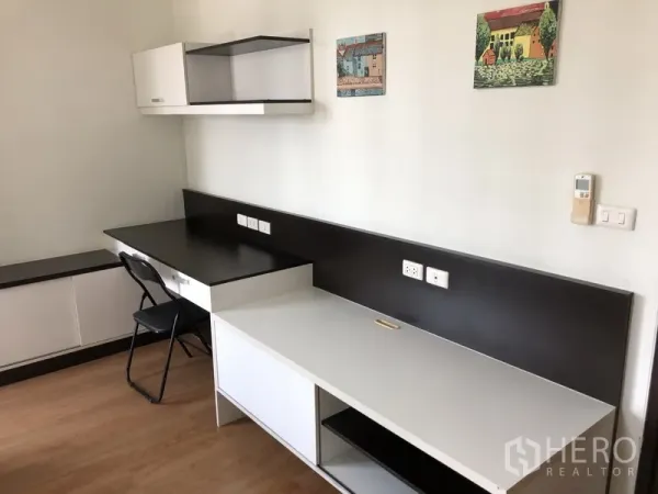 Condominium for rent in Khlong Toei, Bangkok - Built-in study area with long desk, wall shelves, ample power outlets, and wood flooring.