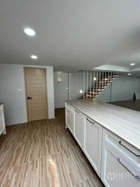 ทาวน์เฮาส์ ขายในPhra Khanong, Bangkok - ห้องครัวเปิดโล่งตู้สีขาว เคาน์เตอร์ลายไม้ พร้อมบันไดในทาวน์เฮ้าส์พระโขนง