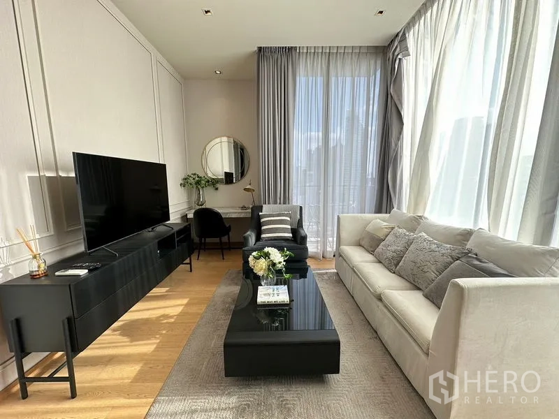 Condominium for rent in Pathum Wan, Bangkok - Living area with long TV console, coffee table, sofa and a work desk by the window.