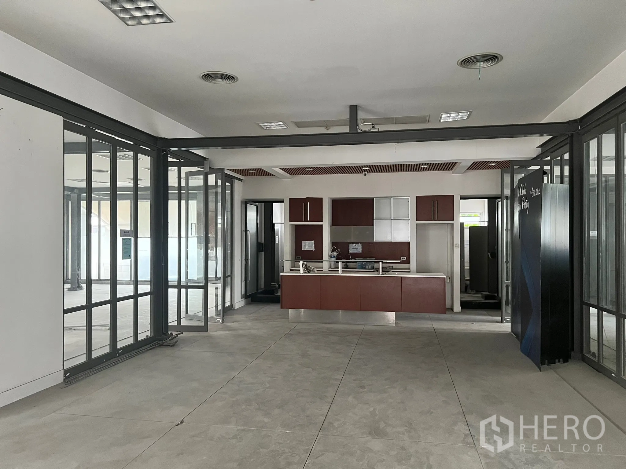 零售空间 出租在Watthana, Bangkok - 宽敞的零售空间内景，带内置吧台、玻璃隔断和水泥地面