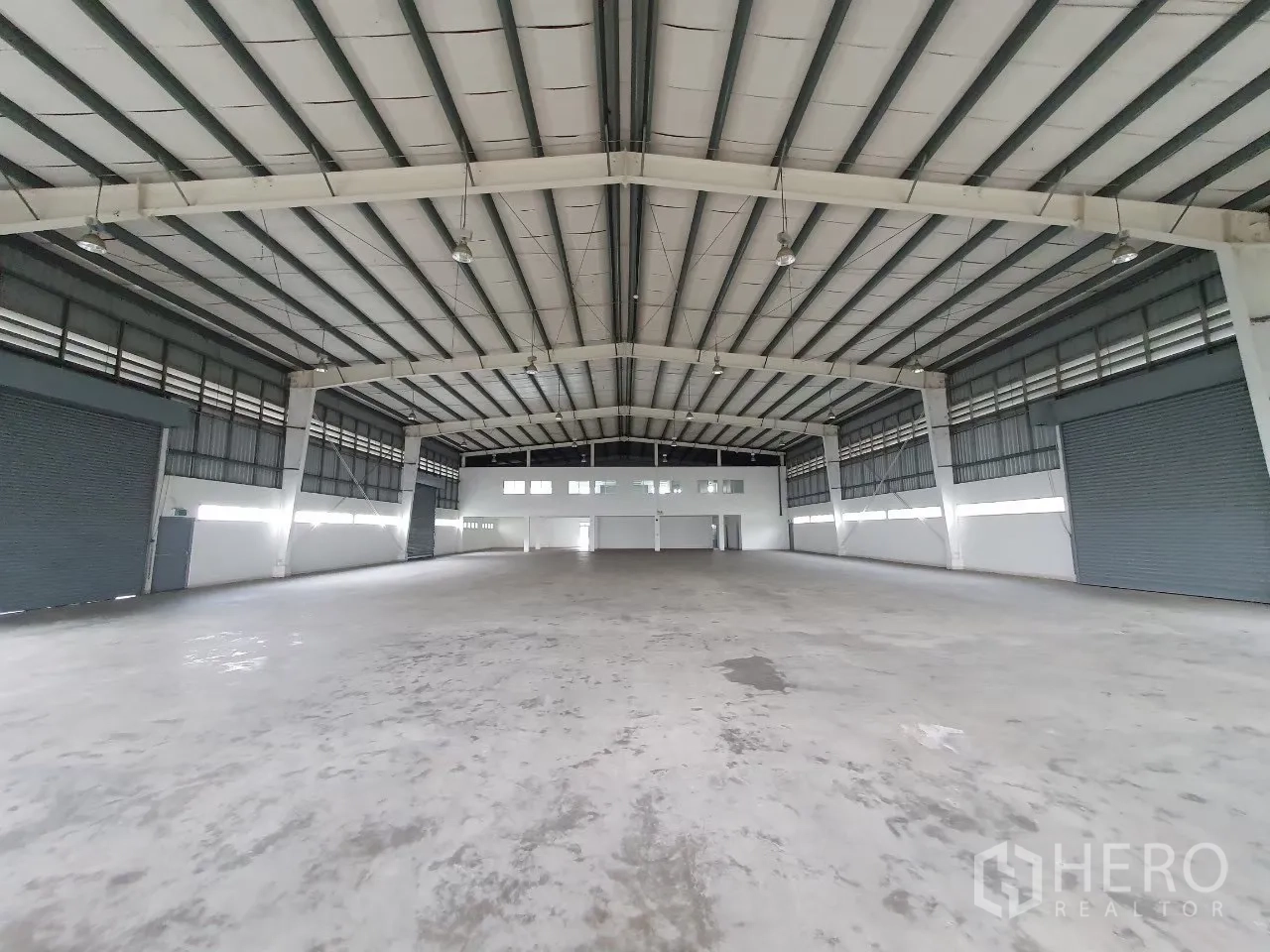 Factory for rent in Bang Pa-in, Phra Nakhon Si Ayutthaya - Open production hall with steel truss roof and multiple roller shutter doors.